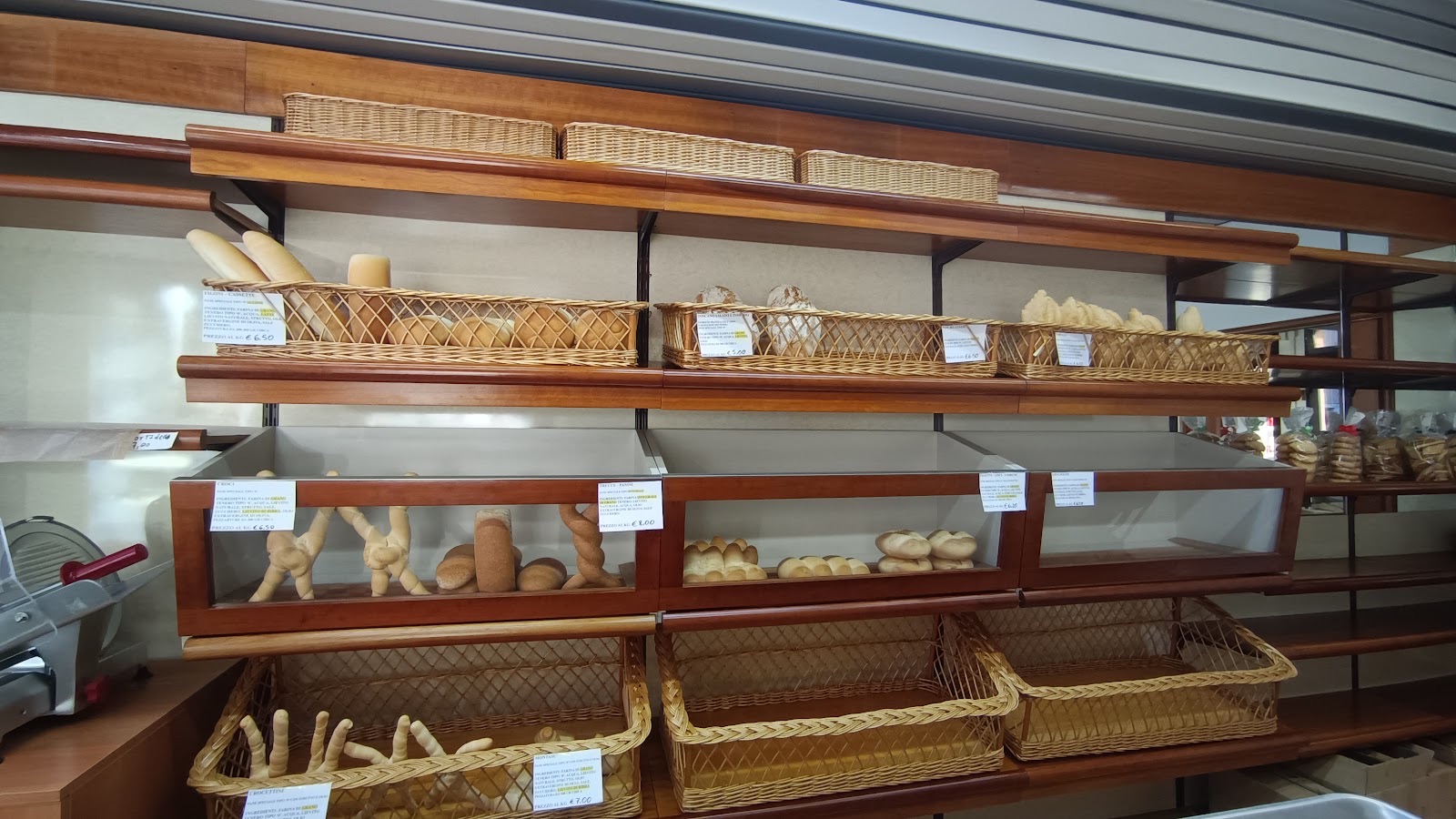 Gli scaffali del Forno Bertolini con il pane nei cestini di vimini e i cartellini degli ingredienti.